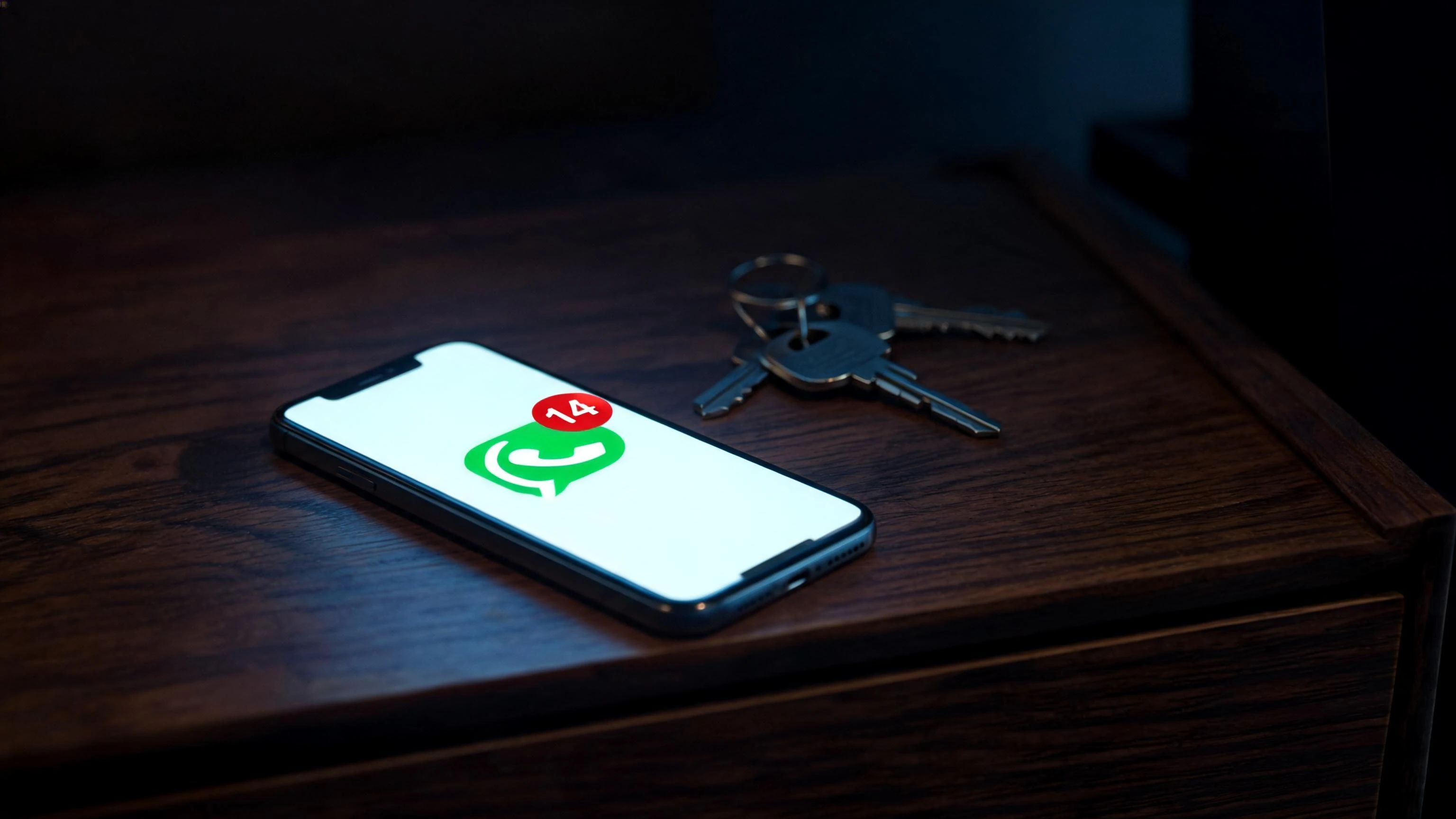 Celular con 14 mensajes de WhatsApp sin contestar junto a unas llaves, leads inmobiliarios sin atender en México